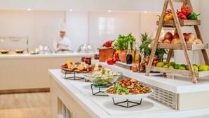 Montaje de bufé con diferentes alimentos y un chef al fondo.