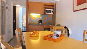 A compact kitchen with a microwave, a sink, and a dining table with chairs. - VVF Dordogne Lot, Martel-Gluges (Montvalent)