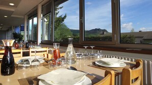 A dining table set for a meal with a view of a mountainous landscape through large windows.