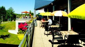 An outdoor patio area with tables and chairs, yellow umbrellas, and potted plants.