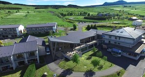 Un bâtiment moderne doté d’une cour intérieure, entouré de champs verdoyants et bordé d’une route sinueuse.