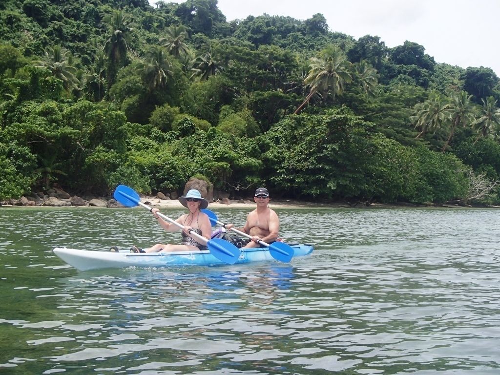 Dos personas hacen kayak en un río tranquilo rodeado de abundante vegetación.