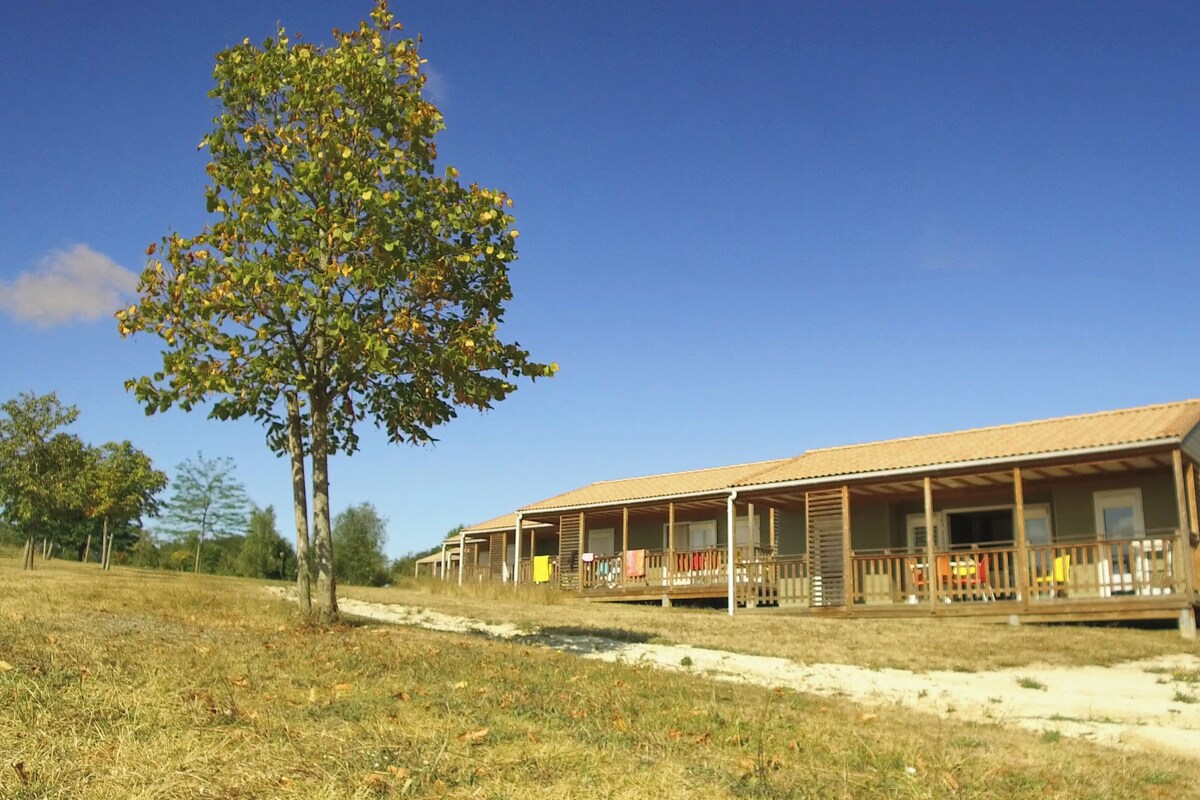 A two-story building with a covered porch and a tree in front.