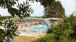 A covered swimming pool with a fenced area and lounge chairs. - VVF Vienne Poitou, la Bussière (La Bussiere)