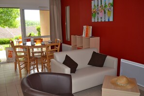 Relax in this stylish living space with a sofa, armchair, and garden view.