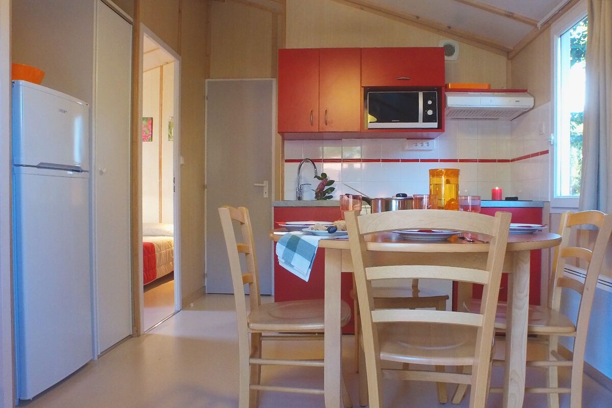A compact kitchen with a microwave, a sink, and a dining area with chairs.