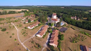 An aerial view of a residential area with houses, a large building with a tower, and surrounding greenery. - VVF Vienne Poitou, la Bussière (La Bussiere)