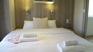 A neatly made bed with white linens, pillows, and two rolled towels. - VVF Vienne Poitou, la Bussière (La Bussiere)