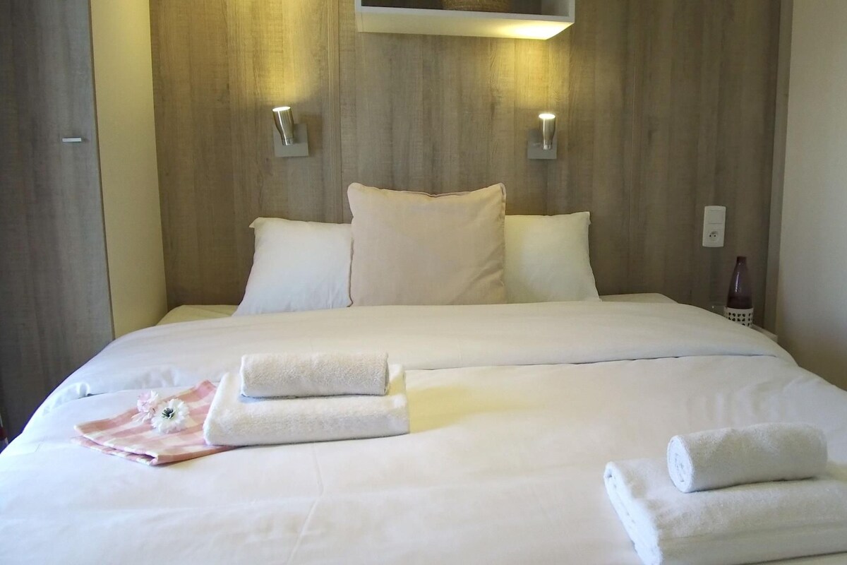 A hotel room with a large bed, two wall-mounted lights, and a bedside table with a vase.