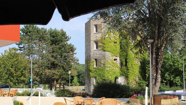 An outdoor seating area with wicker furniture, a building with ivy, and a tree in the background. - VVF Vienne Poitou, la Bussière (La Bussiere)