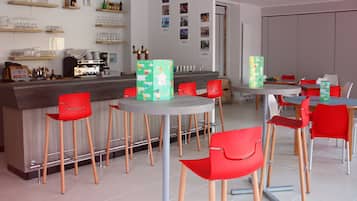 A modern bar area with red chairs, a counter with various bottles, and a coffee machine.