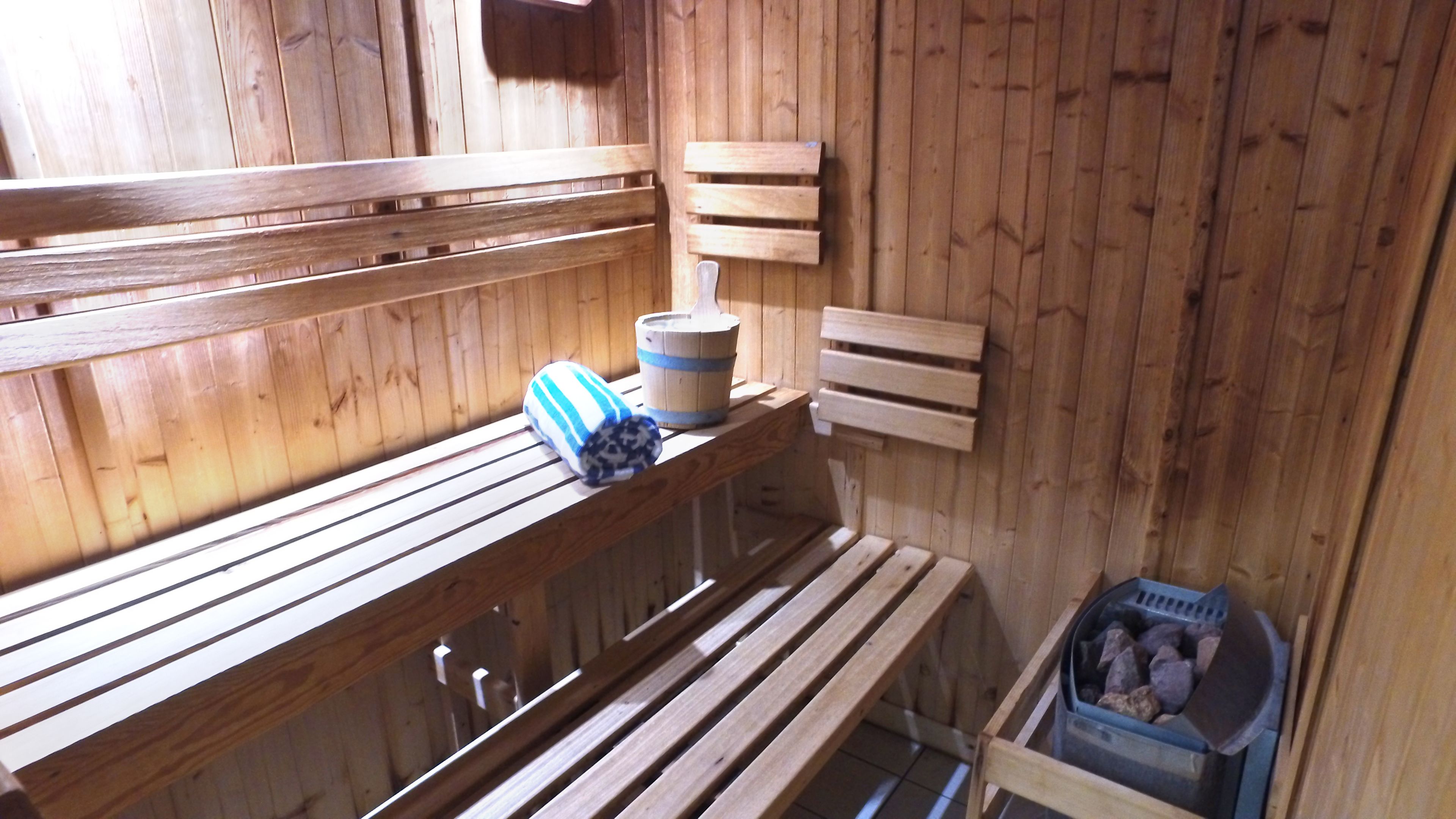Una sauna de madera con bancos, un balde y un bote de basura.