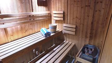 Una sauna de madera con bancos, un balde y un bote de basura.