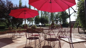 Outdoor seating with red umbrellas and metal chairs. - VVF Bourgogne Auxois Morvan, Semur en Auxois (Le Val-Larrey)