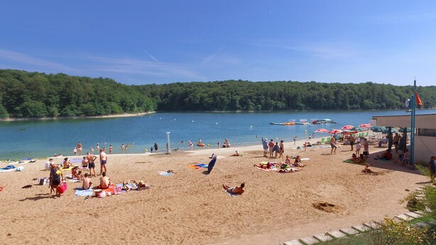A beach with people sunbathing and swimming, surrounded by a forested area and a body of water. - VVF Bourgogne Auxois Morvan, Semur en Auxois (Le Val-Larrey)