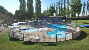 A circular pool with a surrounding deck, lounge chairs, and umbrellas. - VVF Bourgogne Auxois Morvan, Semur en Auxois (Le Val-Larrey)