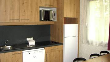 A compact kitchen with wooden cabinets, a microwave, a dishwasher, and a refrigerator.