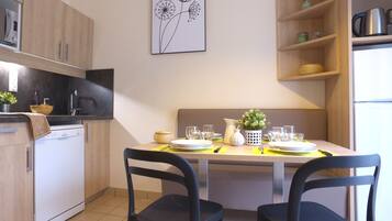 Una cocina moderna con una mesa de comedor preparada para dos personas, que incluye un microondas, un lavabo y armarios de madera.