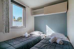 Ein Zimmer mit zwei Betten, einem Vorhangfenster und Blick nach draußen.