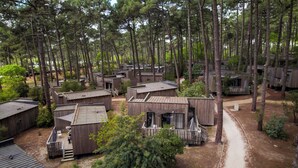 Une zone boisée comprenant plusieurs chalets en bois, chacun doté d’un petit porche et d’une porte.