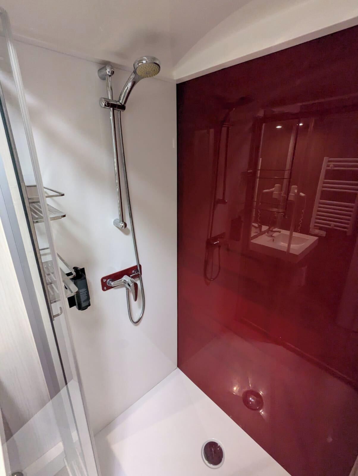 Un baño moderno con cabina de ducha de vidrio, ducha de mano y grifo empotrado.