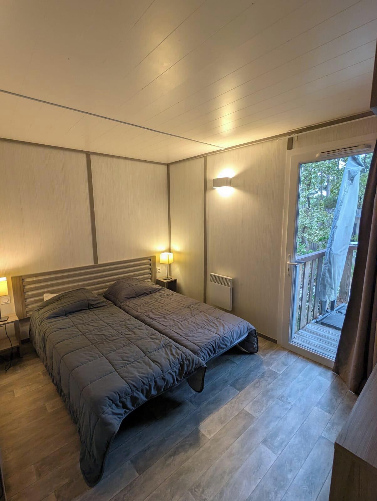 A bedroom with a bed, bedside lamps, a radiator, and a door leading to a balcony.