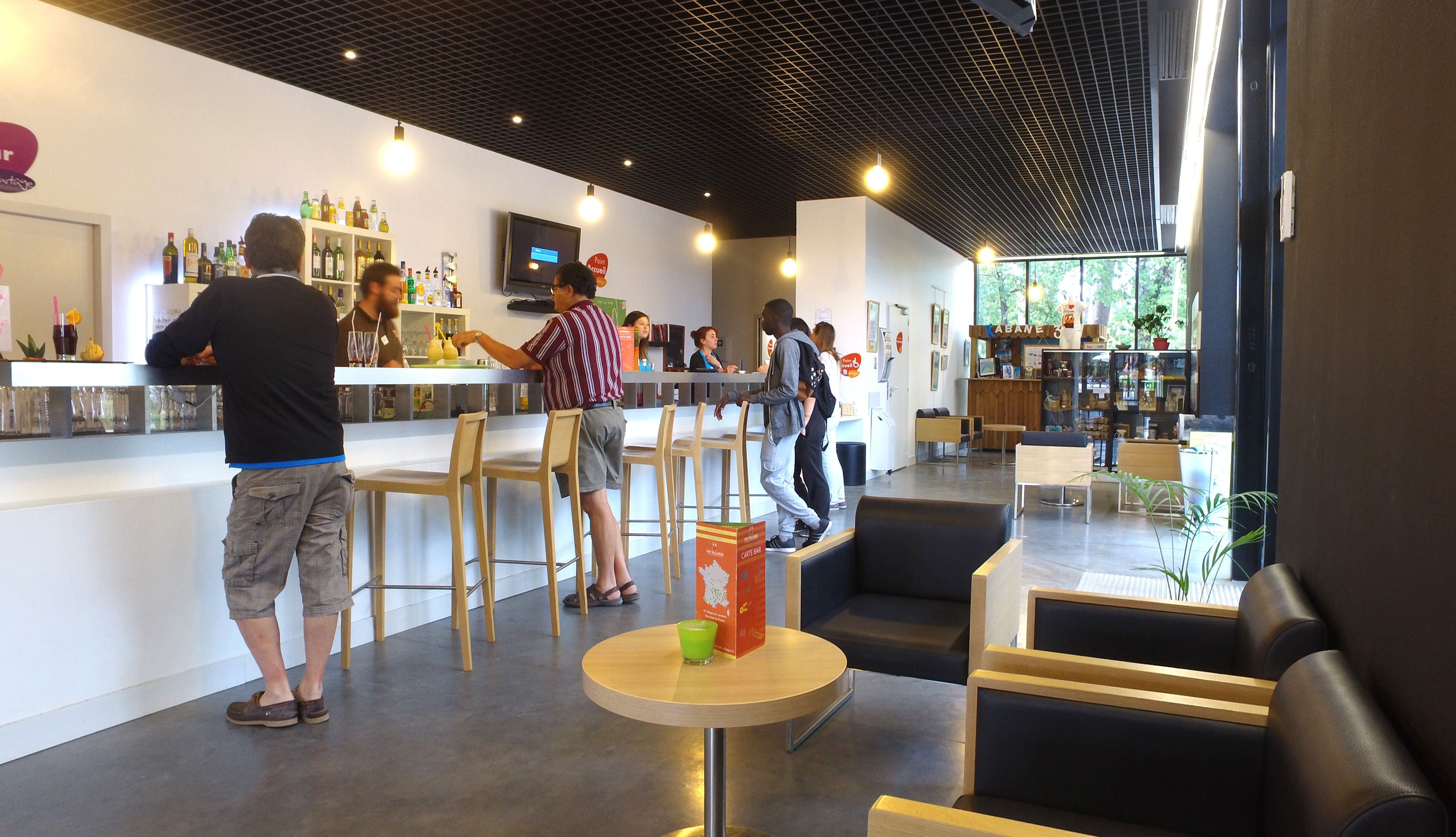 Zona de bar moderna con mostrador, asientos y un ventanal amplio.