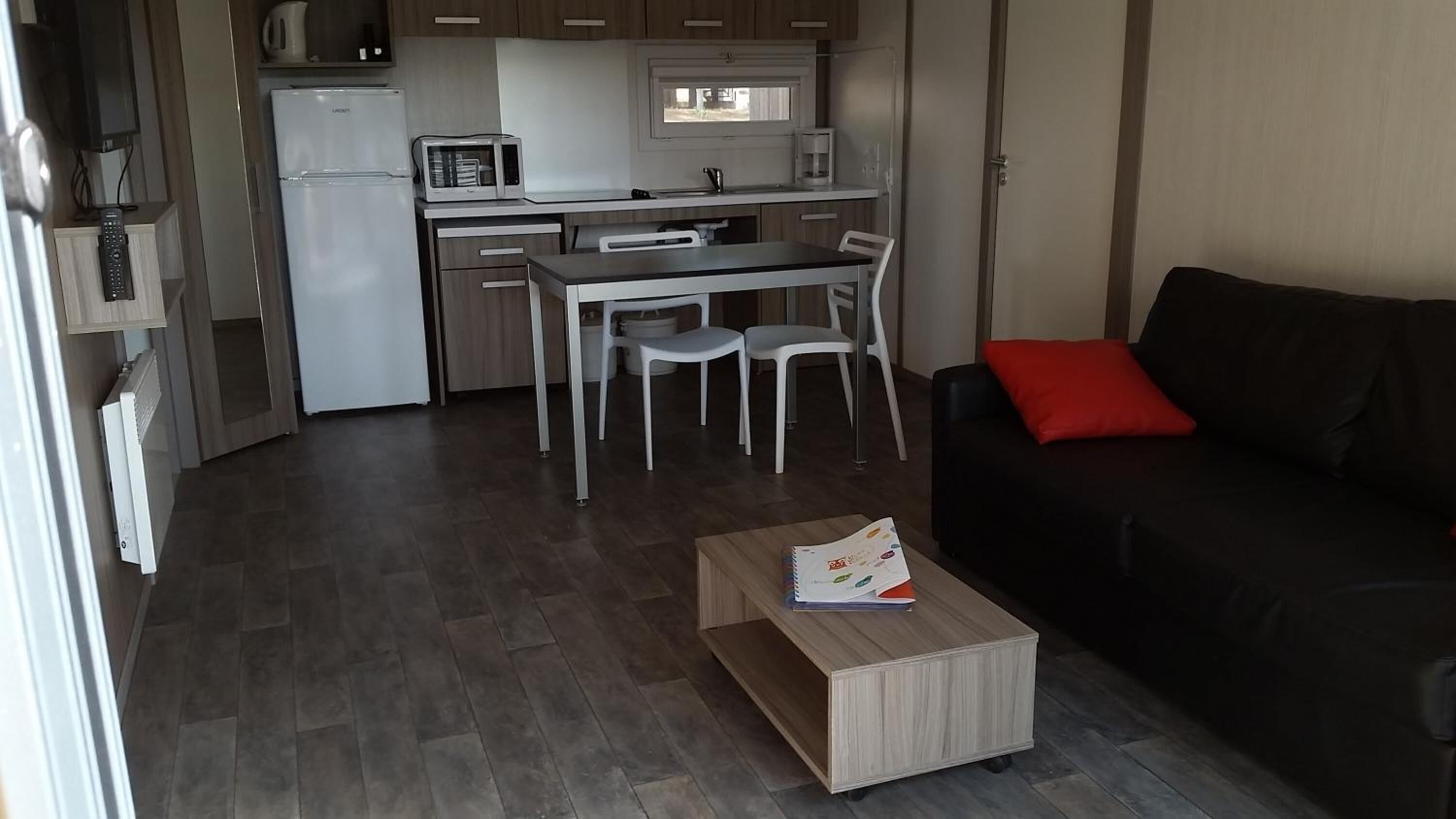 Een ruimtelijk ingerichte leefruimte met kitchenette, eethoek en een zithoek.