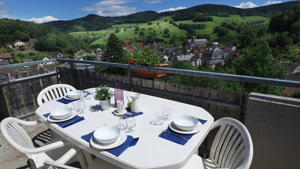 A table set for four with a scenic view of a village and hills in the background. - VVF Alsace Orbey Colmar (Orbey)