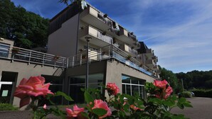 A multi-story building with balconies, large windows, and a parking area. - VVF Alsace Orbey Colmar (Orbey)