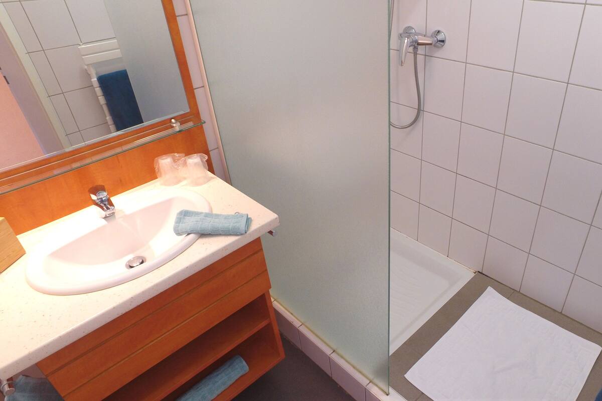 A bathroom with a sink, mirror, and shower.