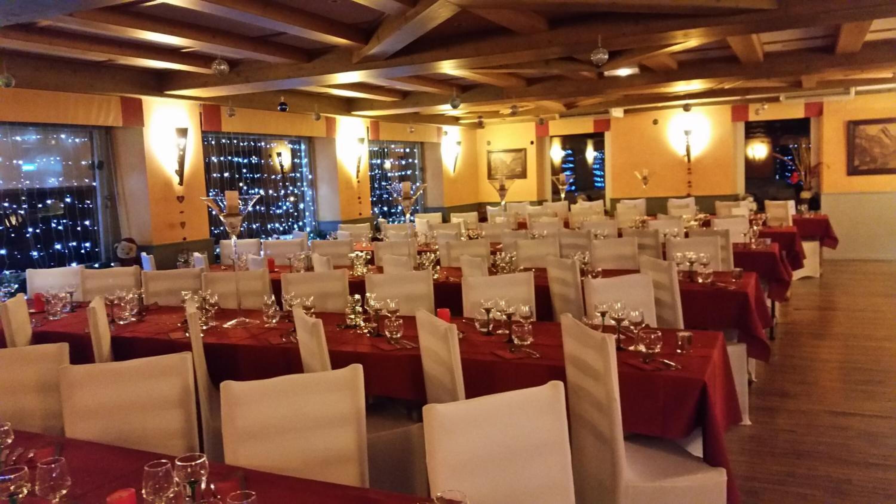A restaurant with multiple tables set for dining, featuring a view of the cityscape through large windows.