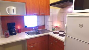 Une cuisine compacte équipée d’une machine à café, d’une bouilloire, d’une cuisinière et d’un réfrigérateur.