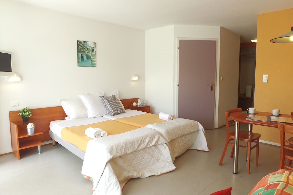 A hotel room with a bed, bedside tables, a desk, and a chair.