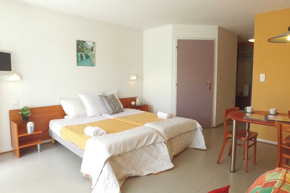 A hotel room with a bed, bedside tables, a desk, and a chair.