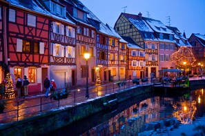 Uma cidade europeia tradicional com casas de estrutura de madeira, um canal e luzes festivas.