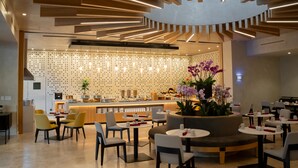 Ein modernes Restaurant mit einer zentralen Sitzgruppe, einer Bar und einer dekorativen Decke.