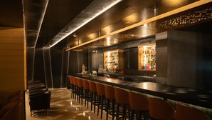 Eine Bar mit einer langen Theke, mehreren Hockern und einer mit Flaschen gefüllten Bar.