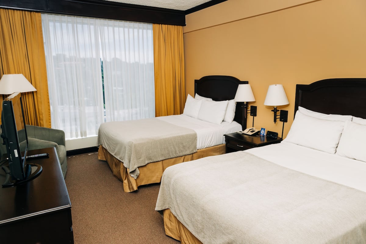 Habitación de hotel con dos camas, un escritorio y una silla.