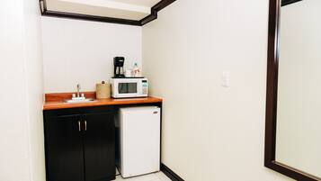 A compact kitchenette with a microwave, coffee maker, and a small refrigerator.