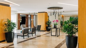 Eine moderne Lobby mit Sitzgelegenheiten, Blumentöpfen und einem großen Spiegel.