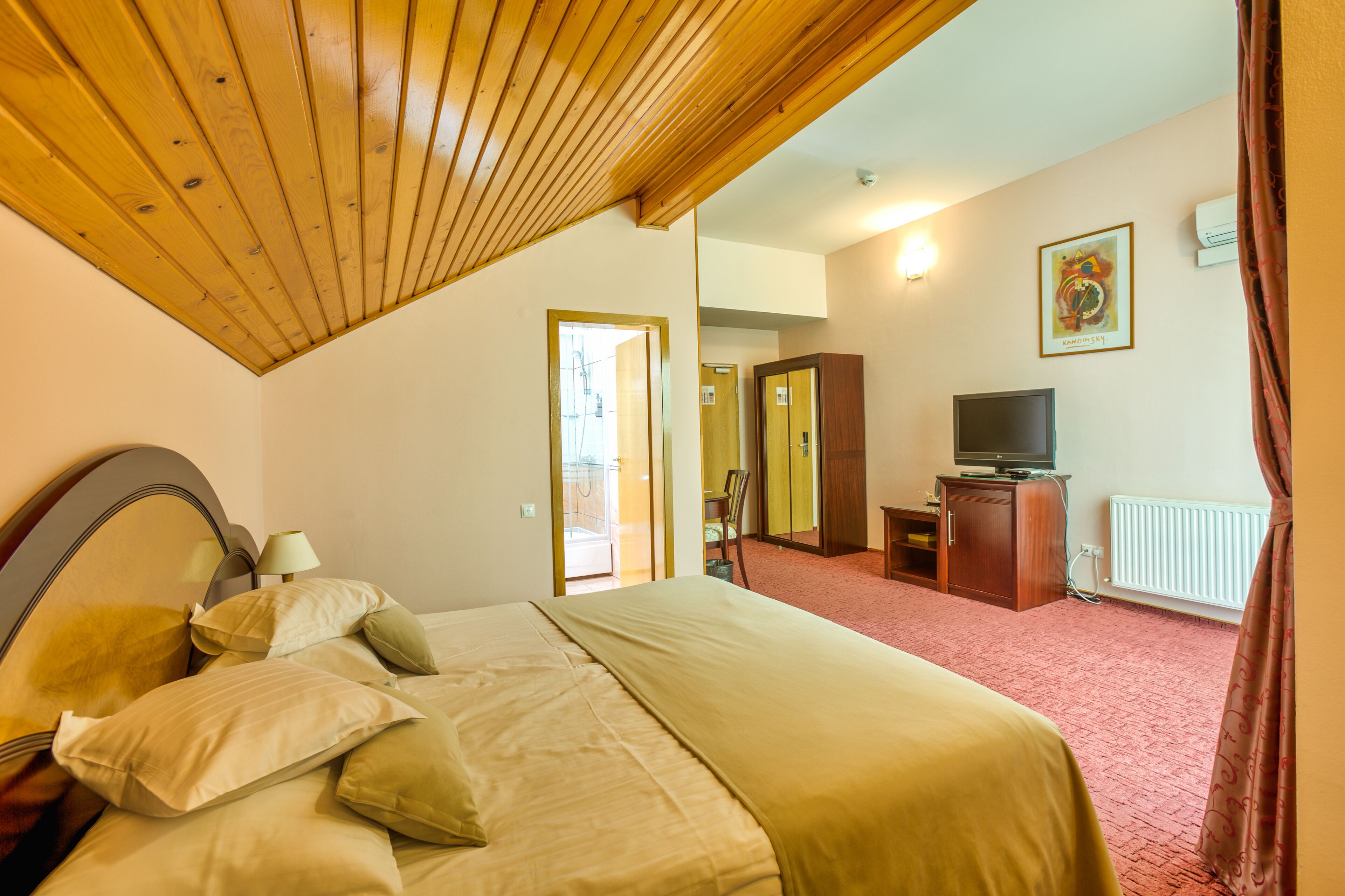 A hotel room with a bed, a television, a wardrobe, and a radiator.