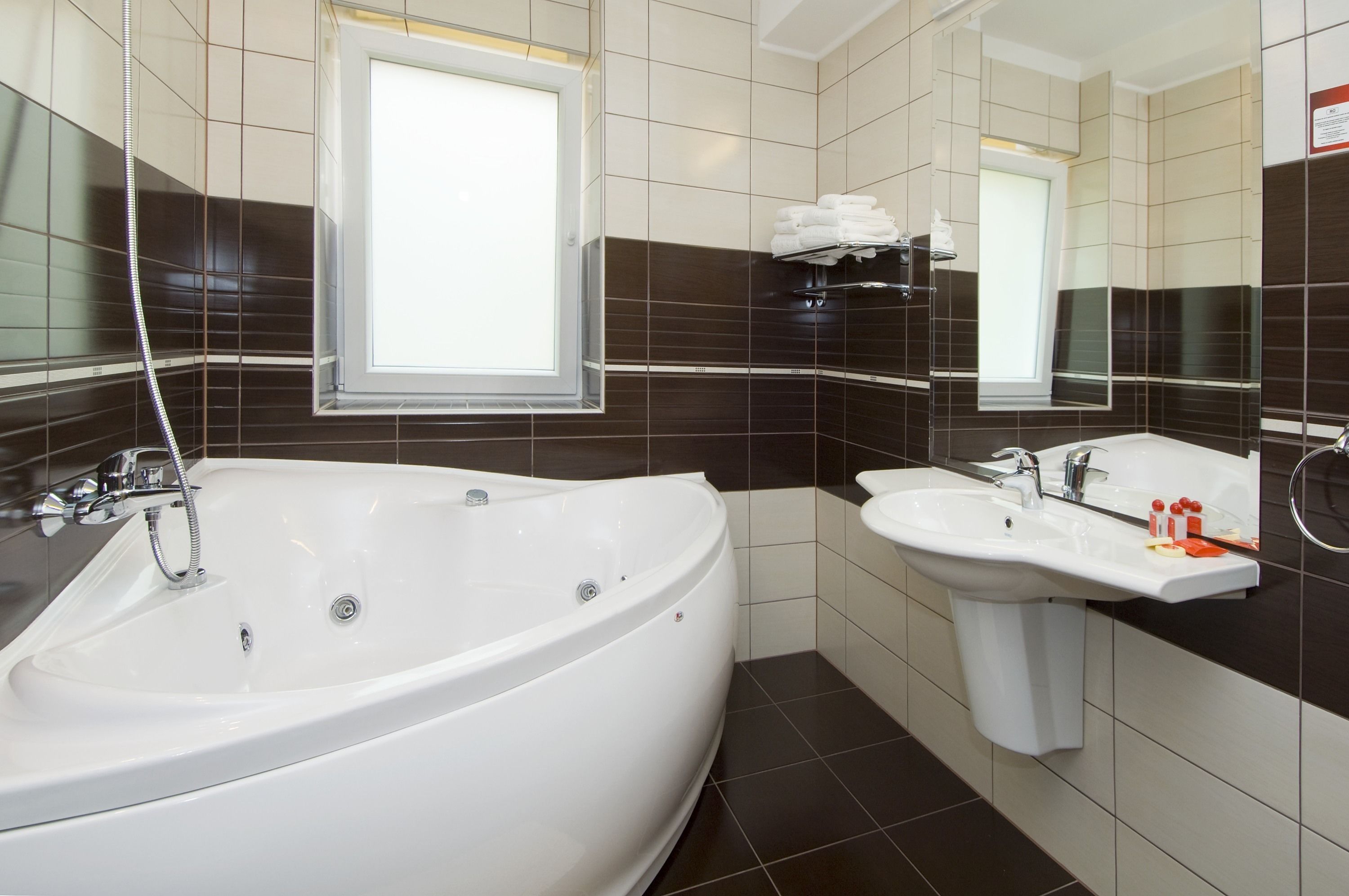 A modern bathroom with a large bathtub, a sink, and a window.