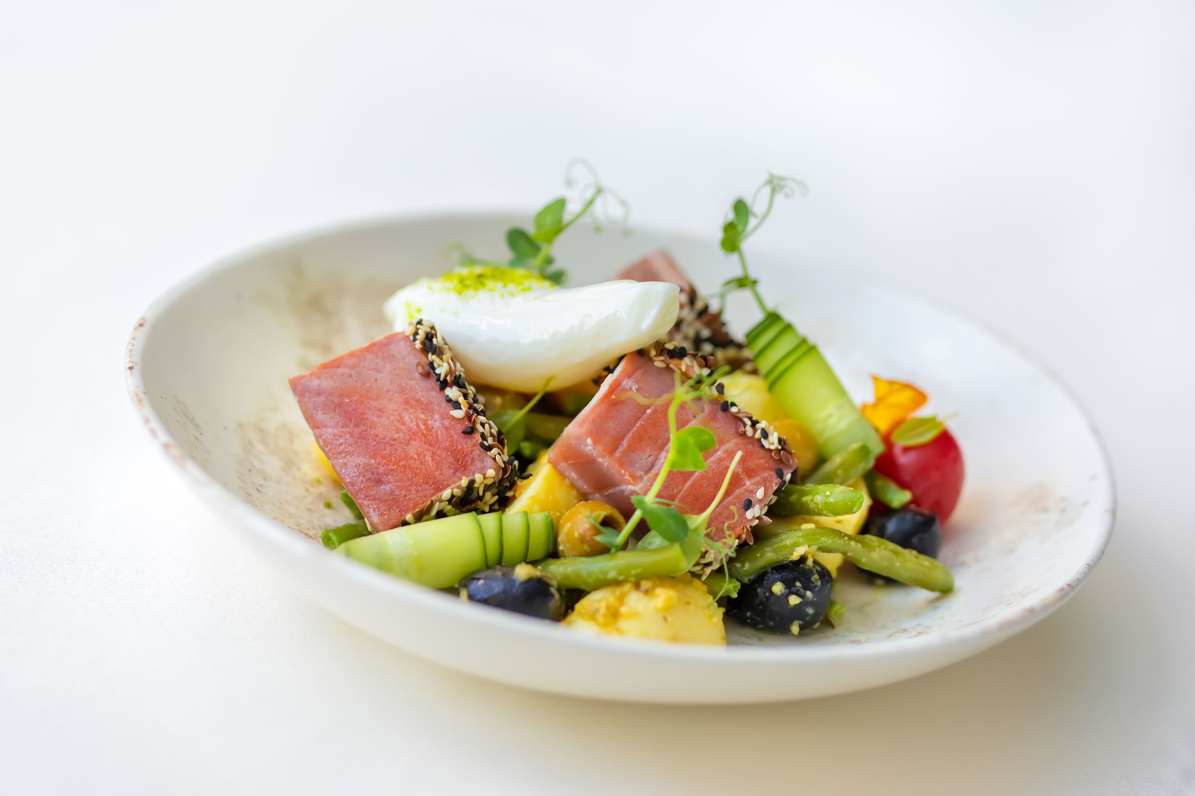 A plate of food with various vegetables, meat, and a poached egg.