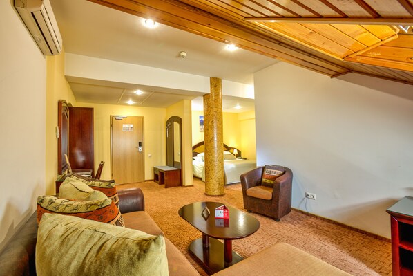 Habitación de hotel con techo de madera, un pilar grande, una cama, un escritorio y un sofá.