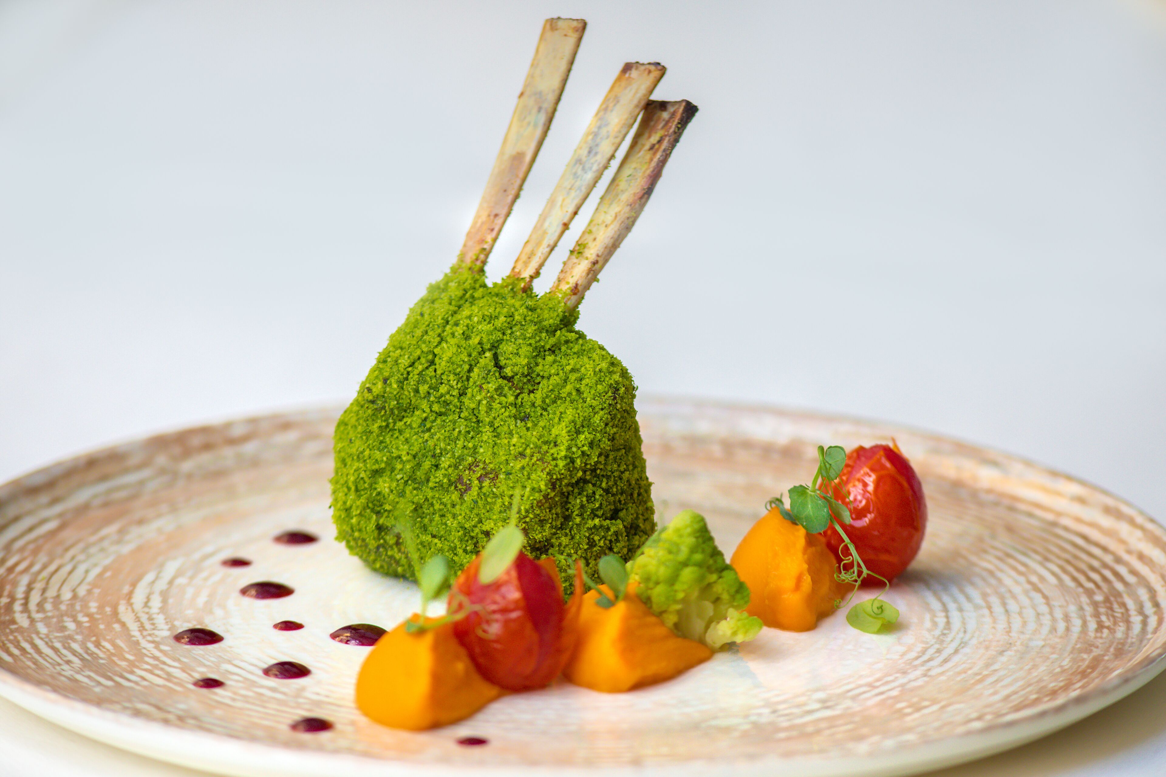 A plate with a green vegetable mound, meat skewers, and various vegetables.