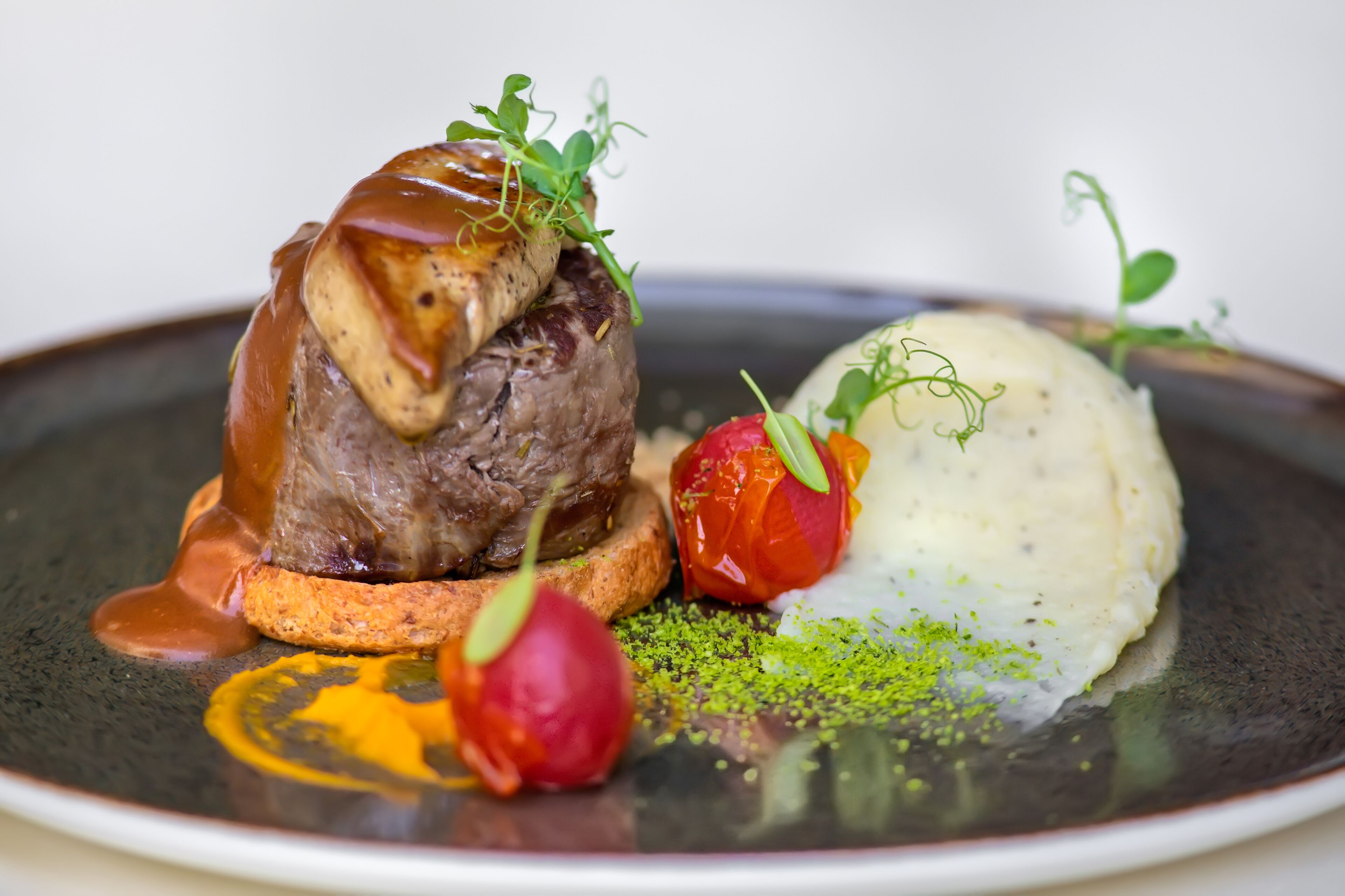 Un plato con un filete de res, puré de papas y guarniciones.