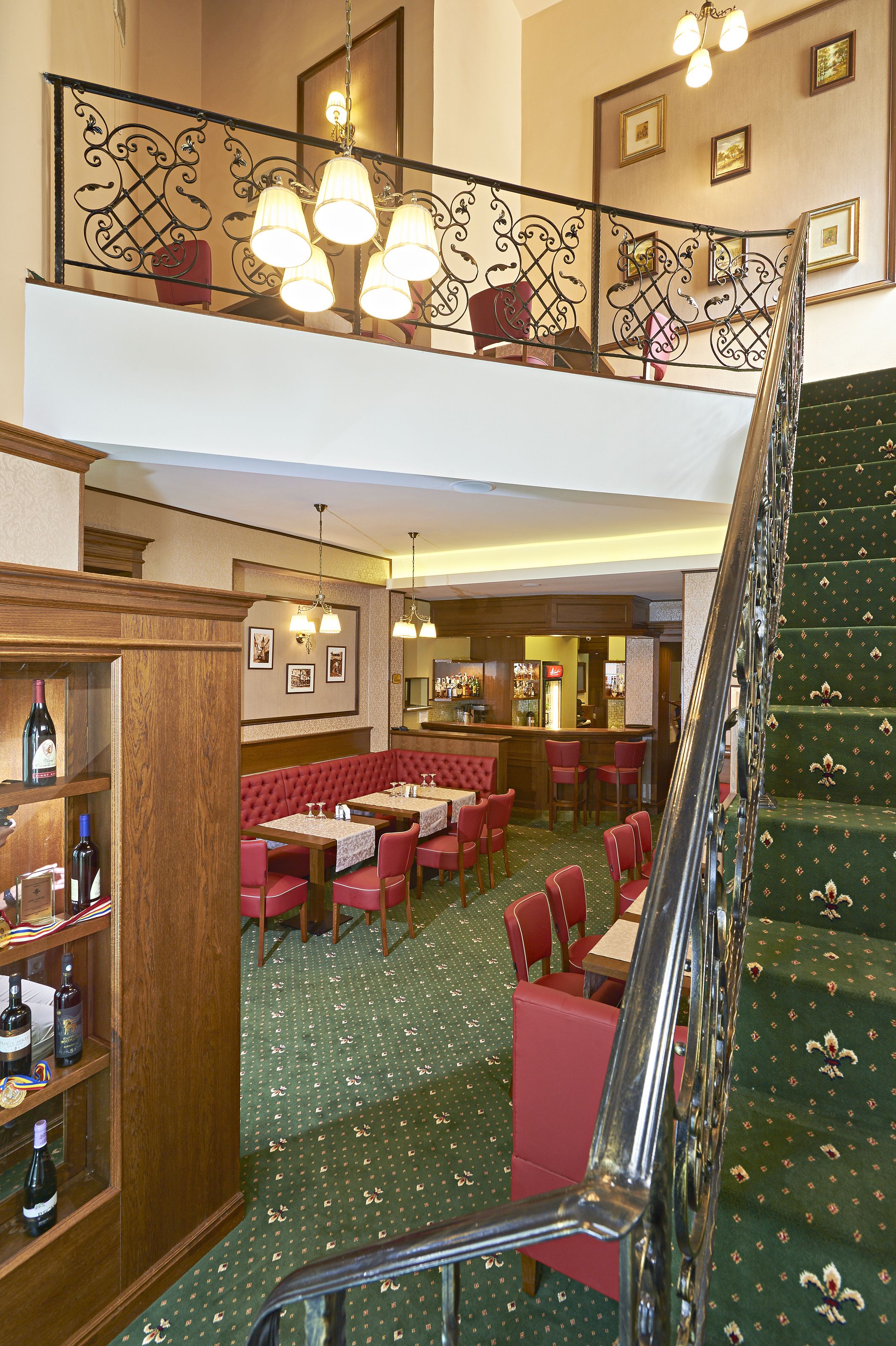 Un vestíbulo de hotel con una escalera, zonas de estar y un bar.