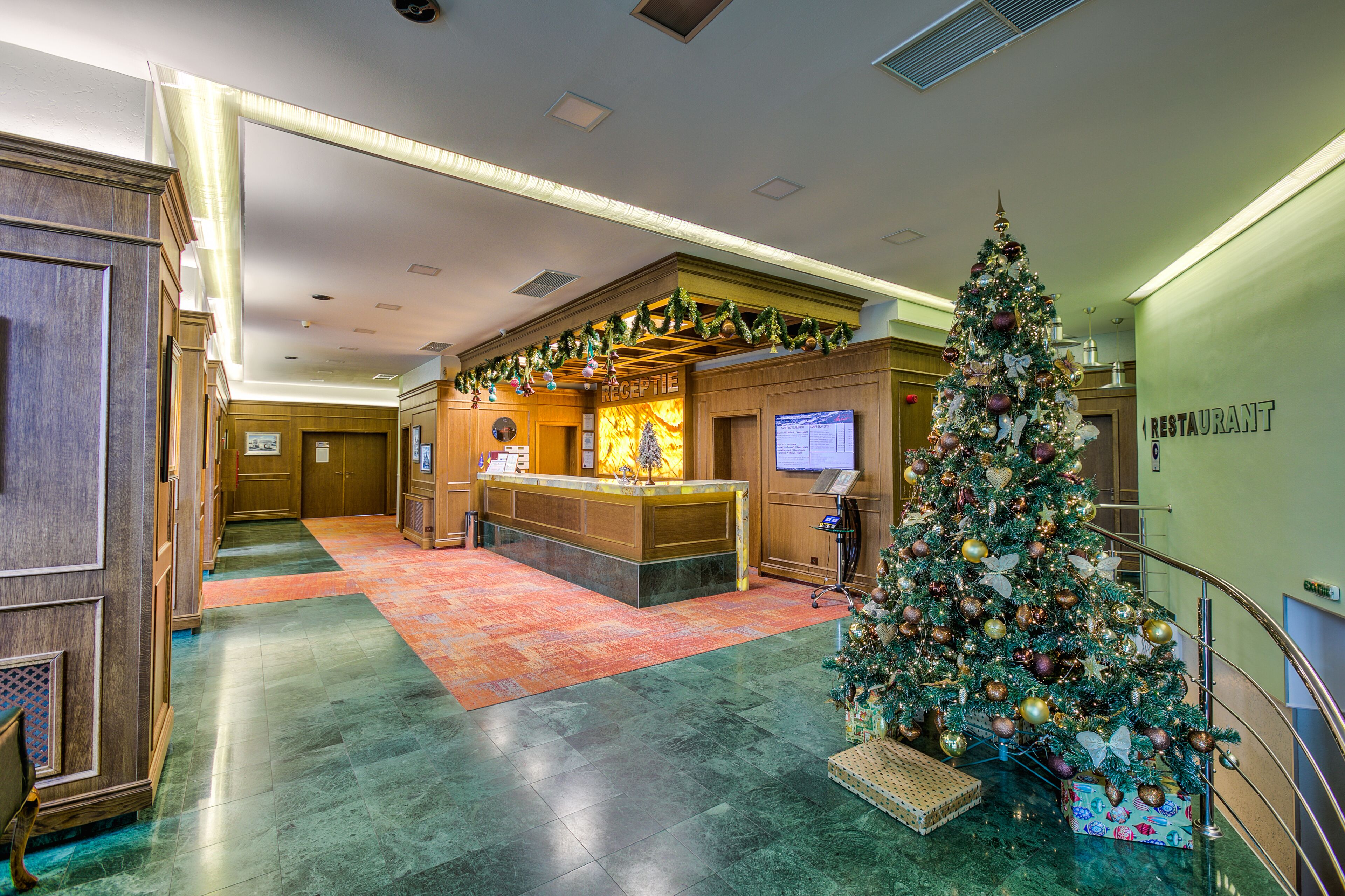 A lobby with a reception desk, a Christmas tree, and a restaurant sign.