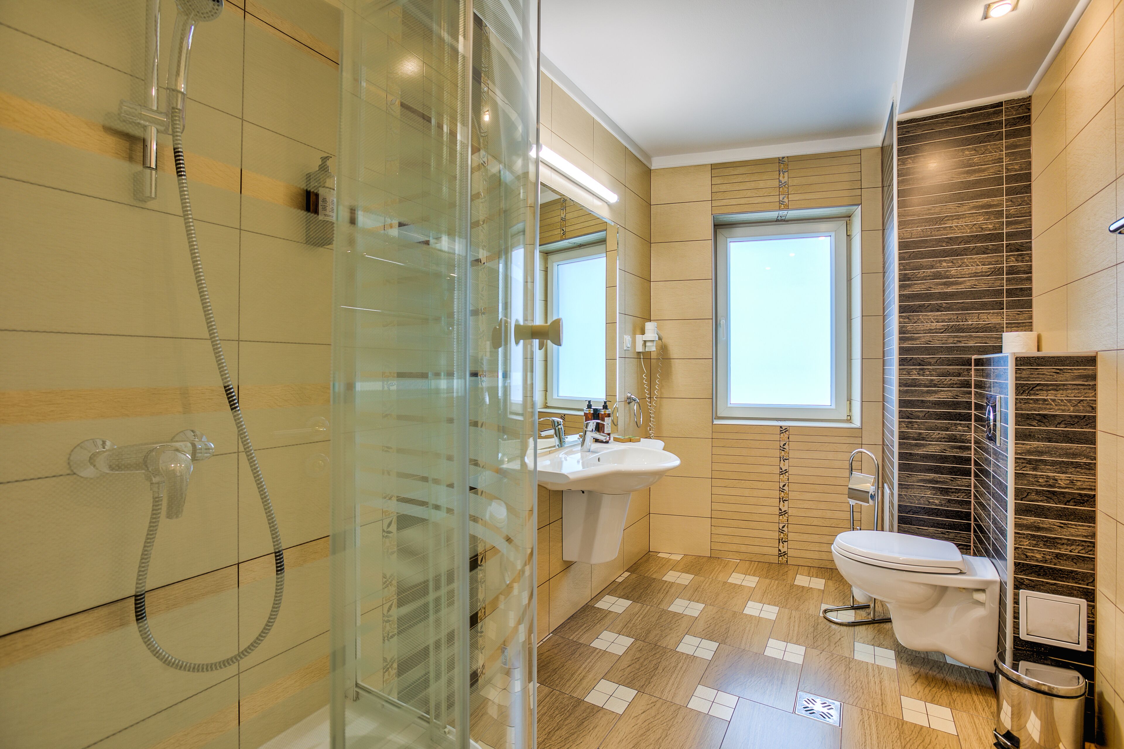 A modern bathroom with a glass shower enclosure, a sink, and a toilet.